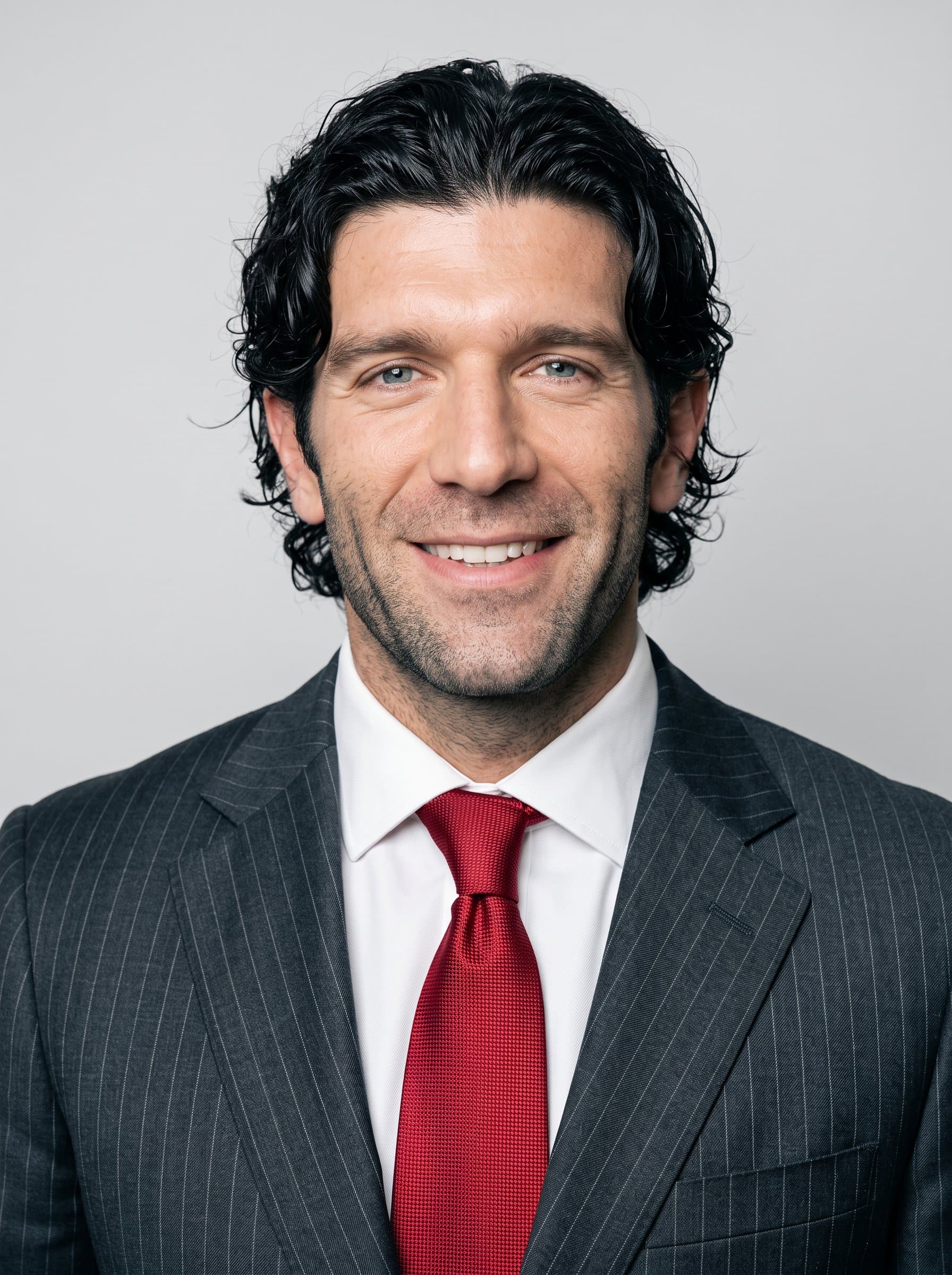 : Highlight an aspiring healthcare leader in a classic pinstripe suit, with a bold red tie as an accent. The light gray background exudes professionalism and allows facial features to stand out.