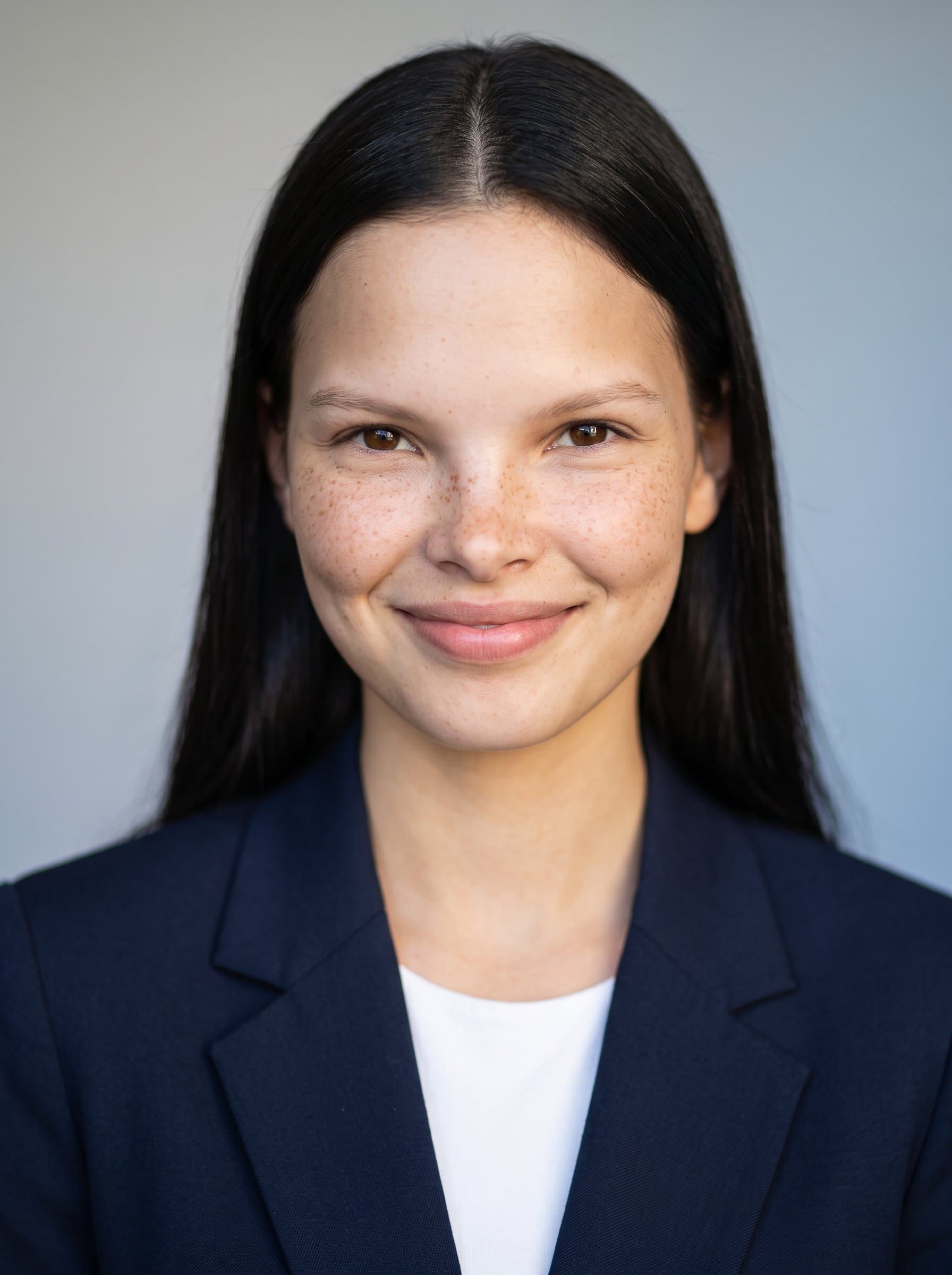: Develop a polished headshot showcasing a relaxed posture and engaging expression. Use diffused afternoon light to create soft shadows, with a smooth, gradient background for contemporary flair.