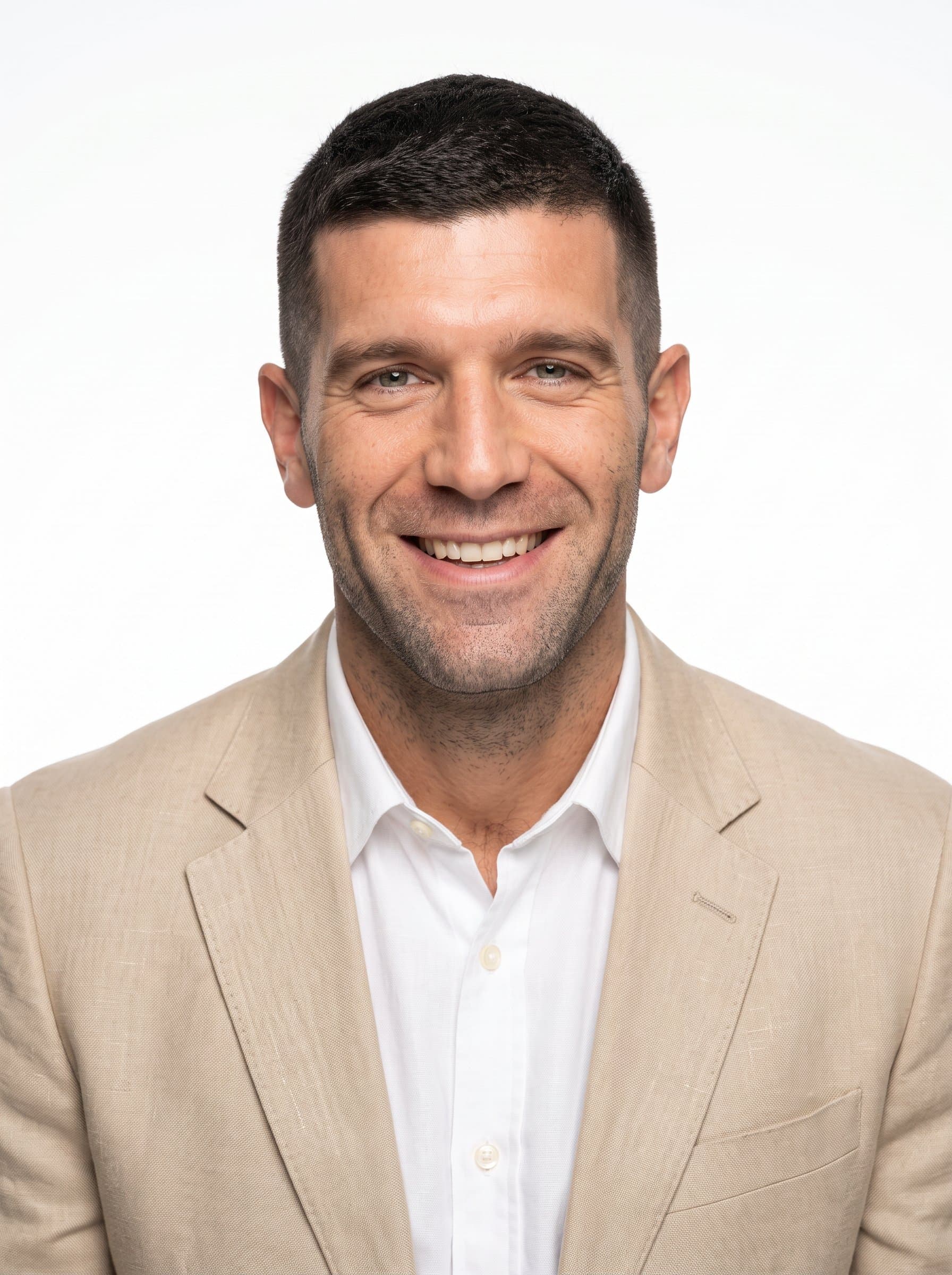 captures an man with a short haircut and an amiable smile, dressed in a beige blazer. The pure white backdrop accentuates their welcoming and approachable personality.