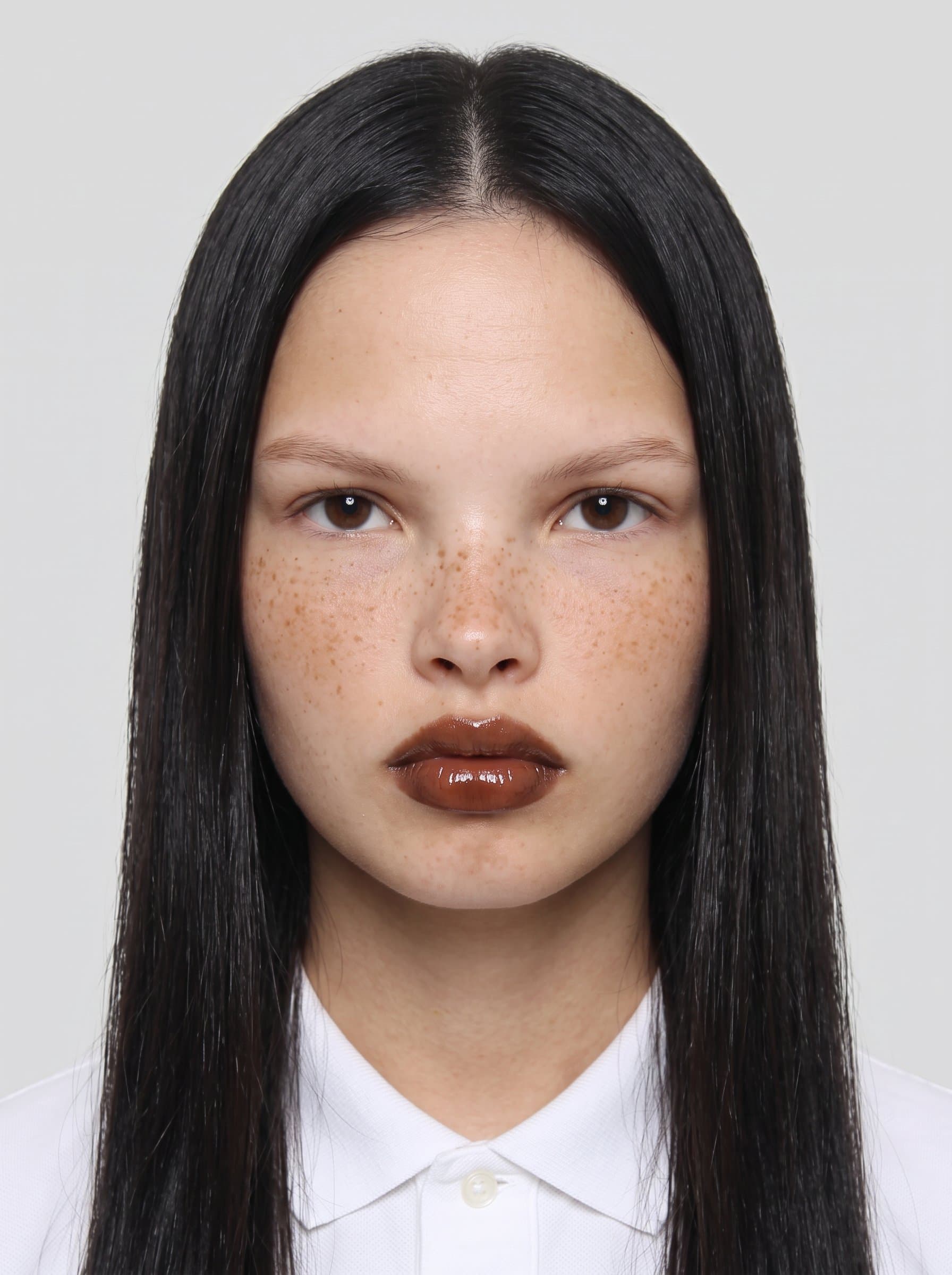 : Develop a photorealistic headshot suitable for passports. Utilize a plain backdrop and ensure the face is evenly lit, centered, and without glasses, maintaining a neutral expression.