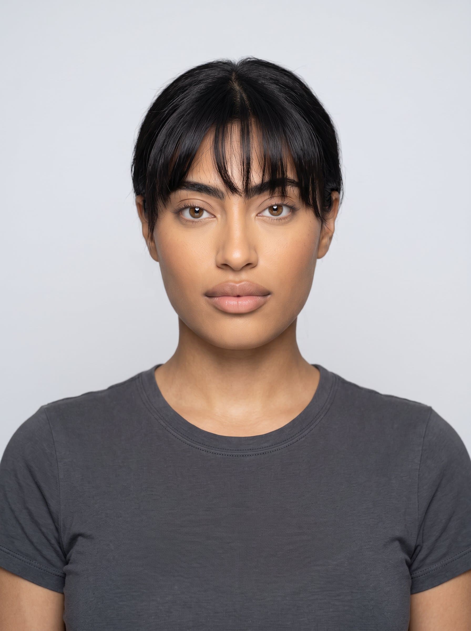 : Generate a photorealistic passport photo headshot with a plain background. Maintain neutral facial expression and centered position, emphasizing even lighting and standard guideline adherence.