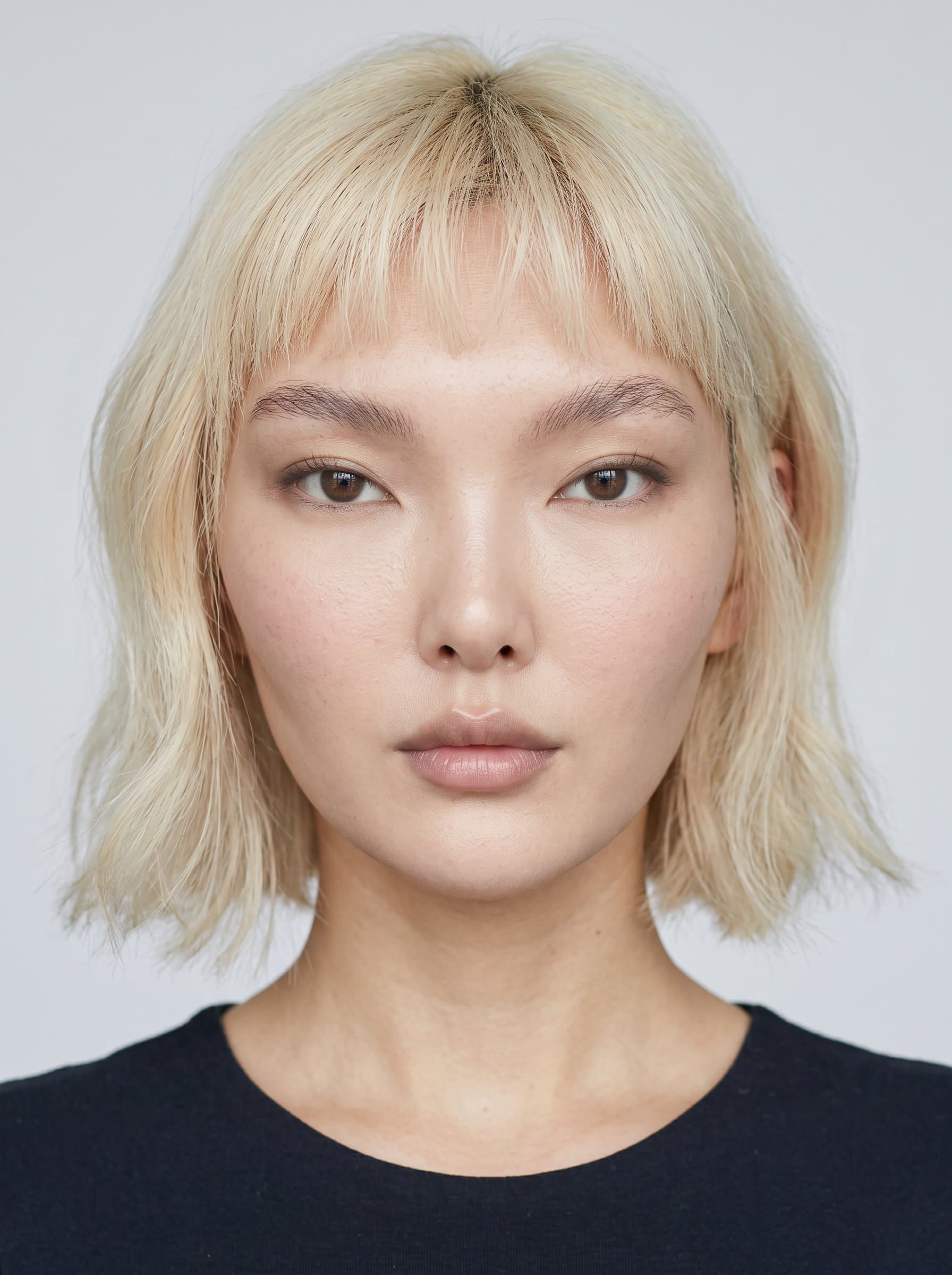 : Develop a headshot with a plain background for a passport photo. Ensure even lighting and a neutral expression, with the face centered to meet photorealistic standards.