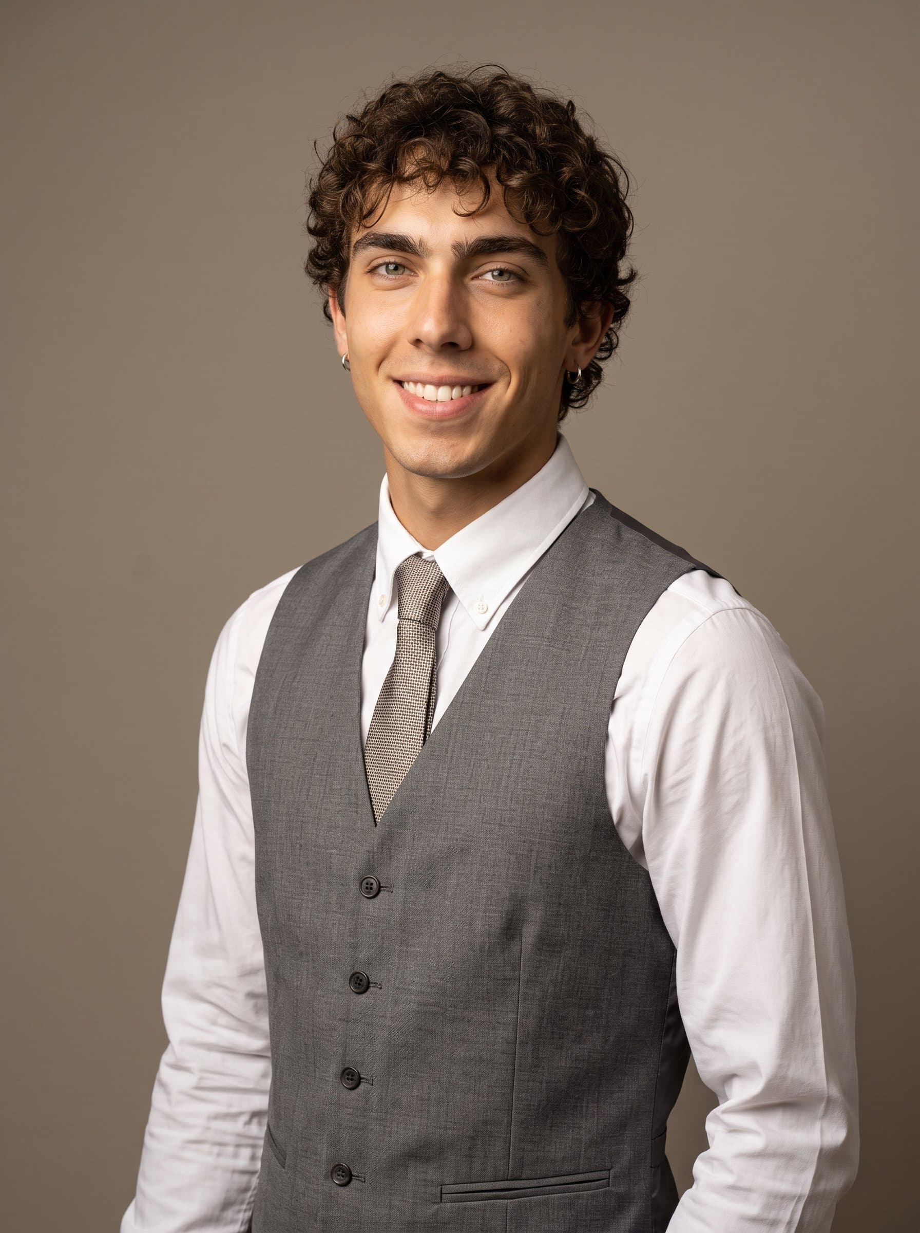 formal appearance in a gray vest, white collared shirt, neutral taupe backdrop, gentle diffused lighting highlights a confident smile, AI captures a genuine essence of academic refinement.