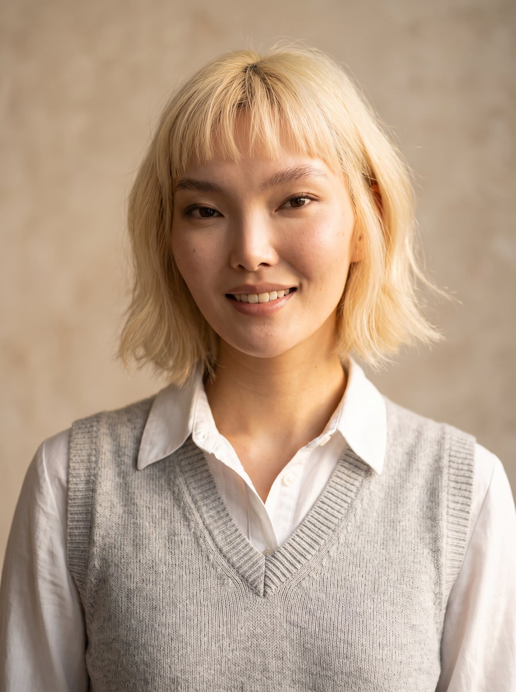 in a light gray vest over a white collared shirt, soft beige backdrop, warm lighting that highlights a hint of a smile, AI-generated to capture scholarly earnestness and future aspirations.