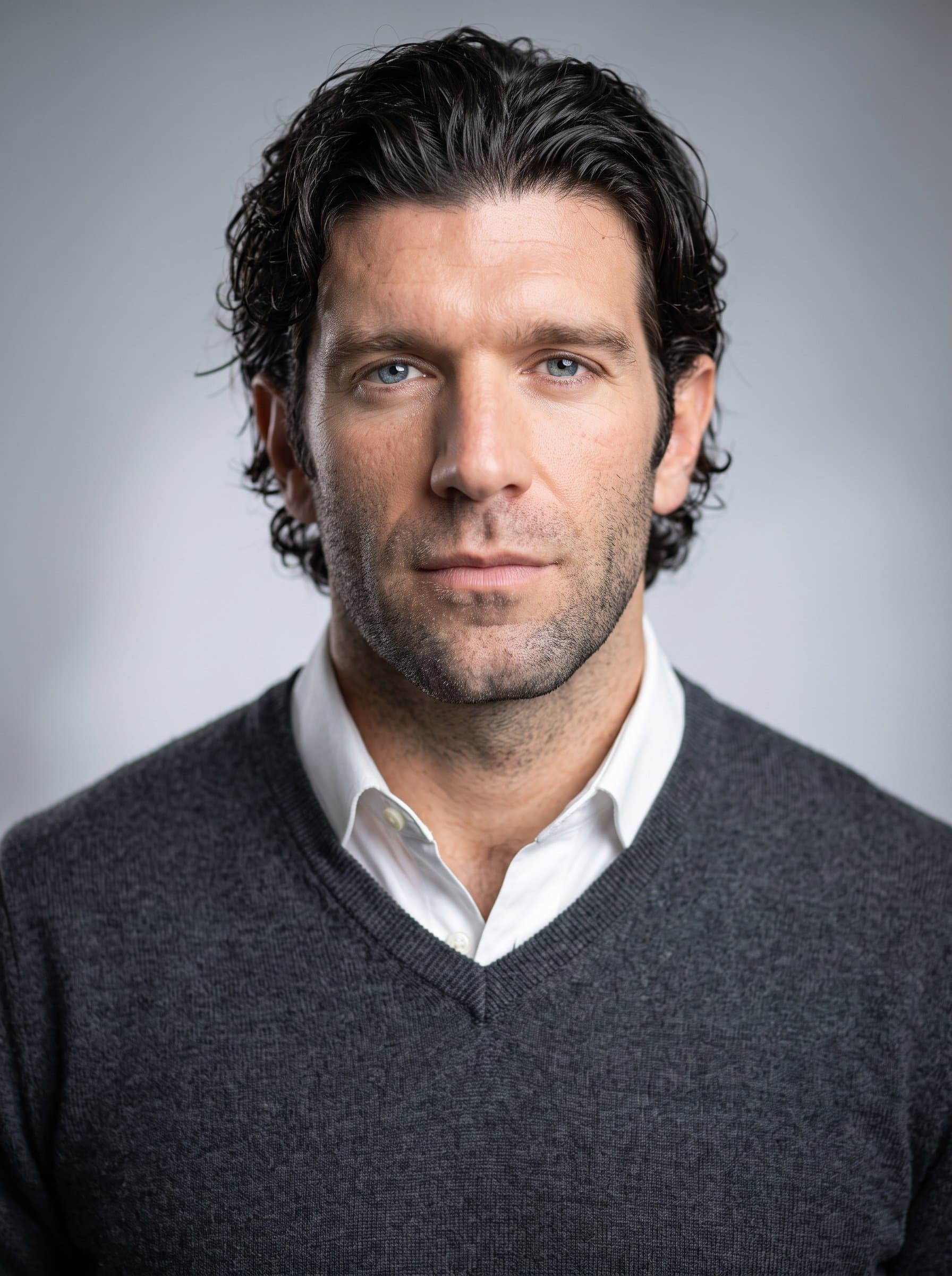 formal headshot style, charcoal gray sweater, white shirt, light gray background, softly focused lighting, AI conveys a balance of youthful determination and academic expertise.