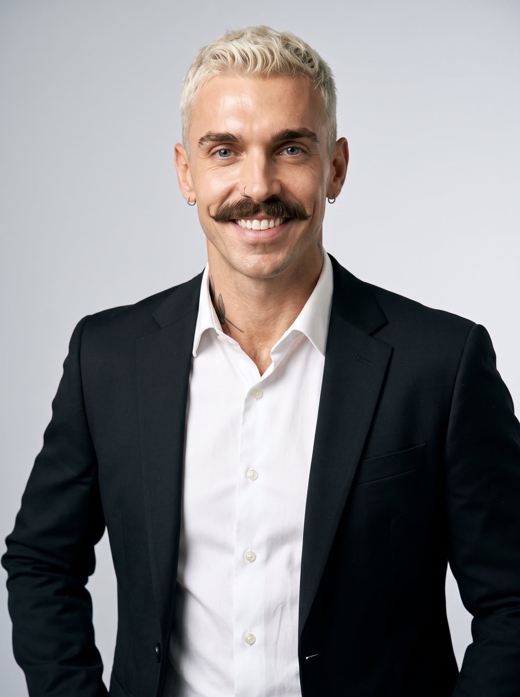 portrayed wearing a sleek black blazer and crisp white shirt, with an inviting smile and a soft grey background, suitable for a professional business card.