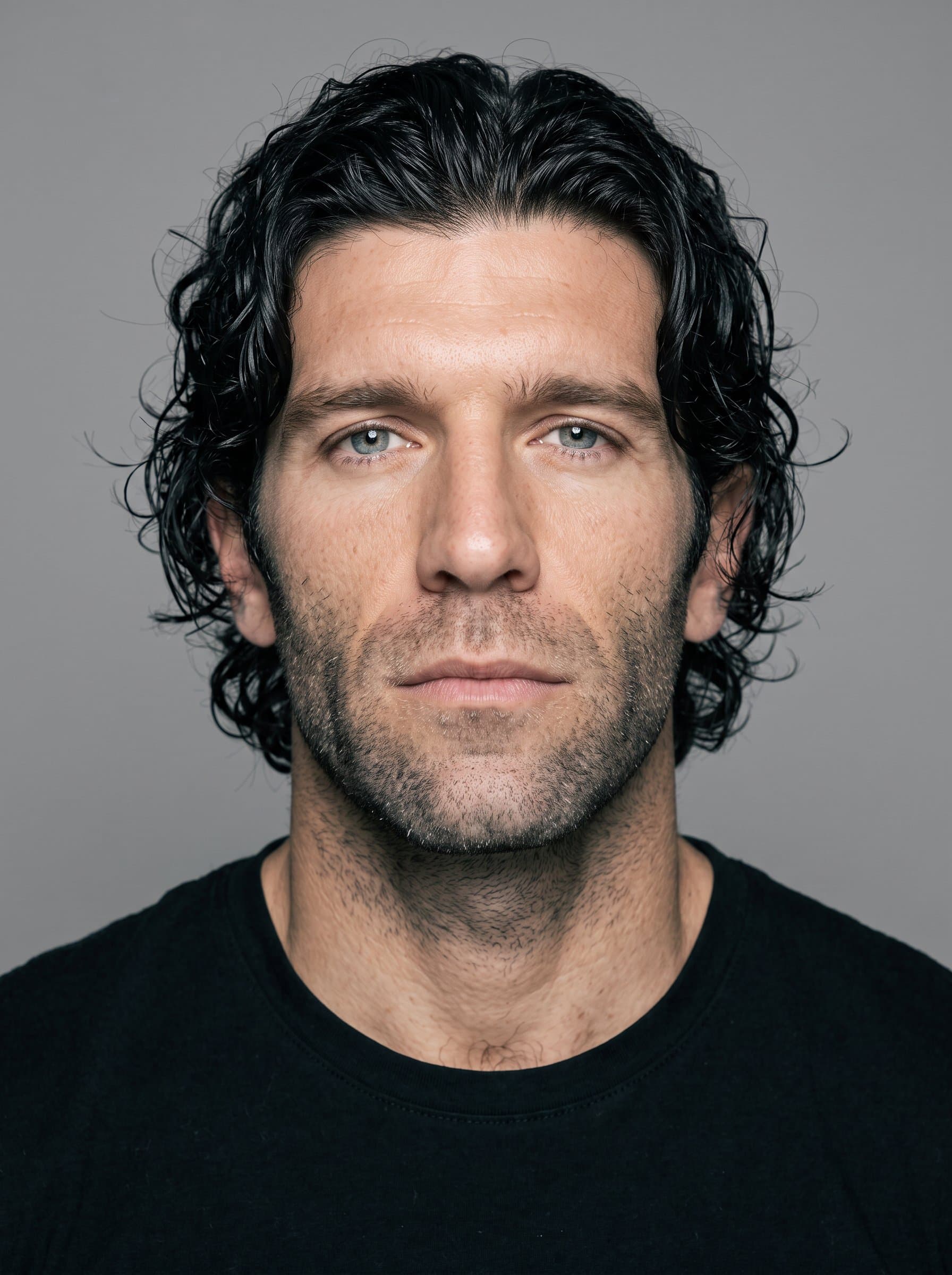 Generate a photo with a plain grey background, maintaining even lighting across the face. The man should have a centered, forward gaze, complying with standard visa photo requirements.