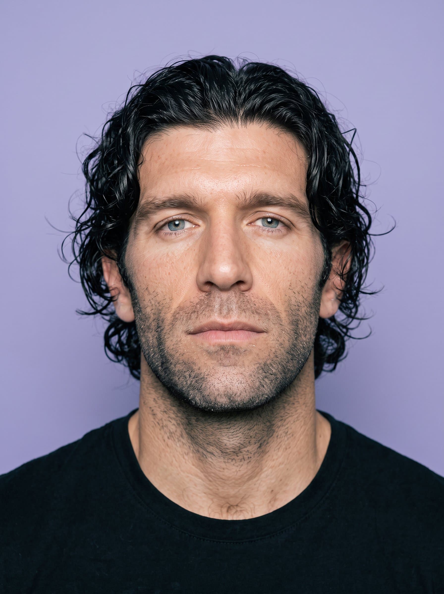 Create a portrait featuring a plain lavender backdrop. The man must have a neutral demeanor, with unobstructed facial visibility, aligning with global travel photo norms.