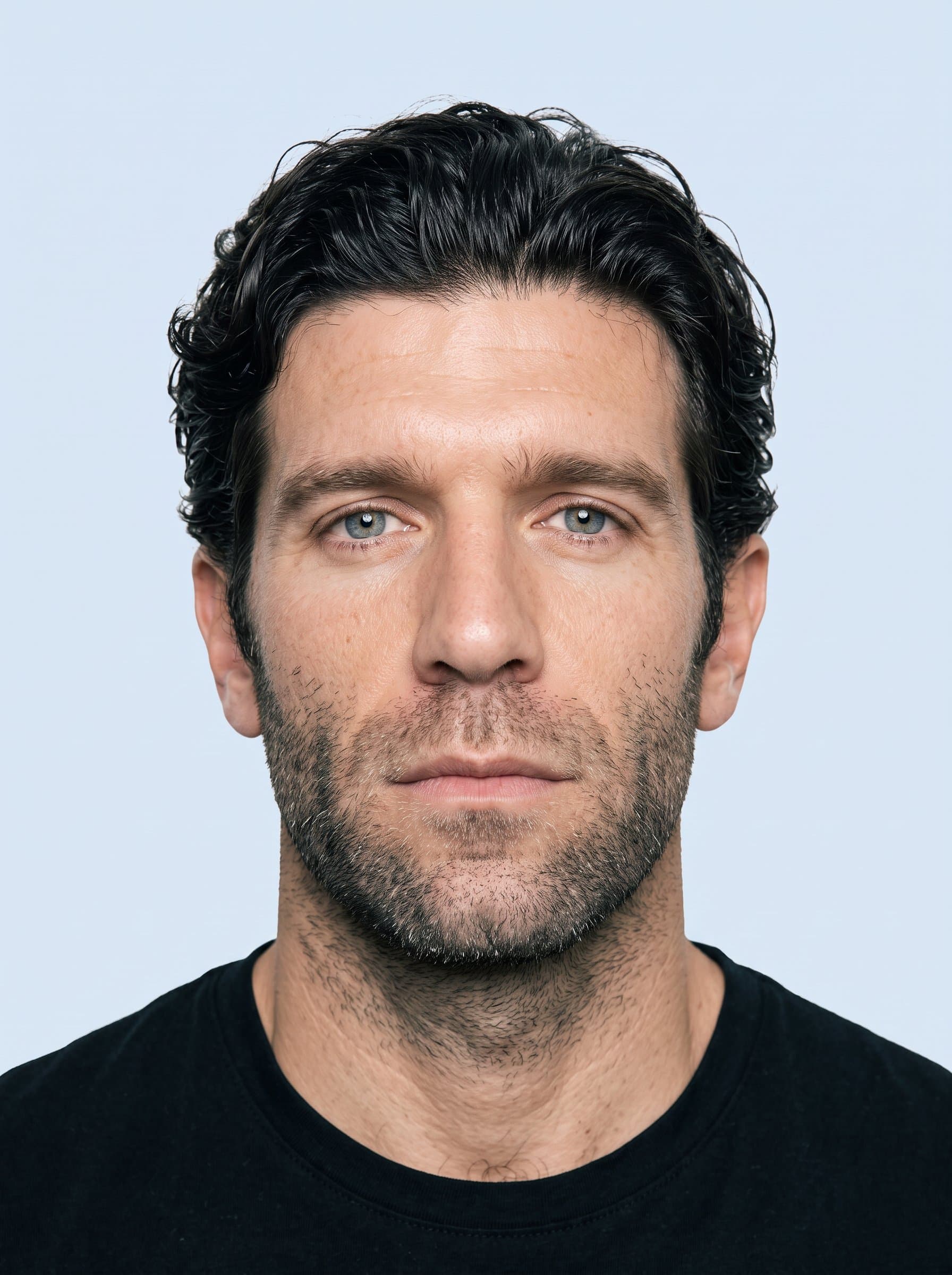 Generate a photo on a plain pale blue backdrop. Position the man's face centrally with clear visibility, adhering to global visa photo requirements.