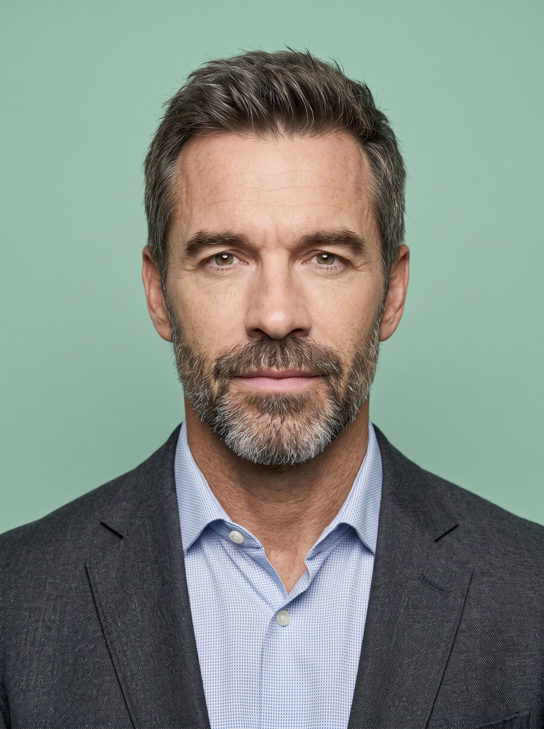 Produce a portrait using a muted mint green background. The man should have a neutral expression and an unobstructed face, conforming to official travel documentation guidelines.
